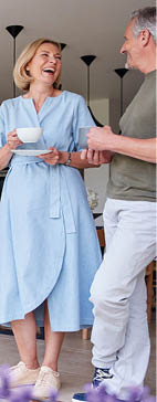 Senior Couple Standing And Looking Out Of Kitchen Door Drinking Coffee